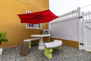 una sombrilla roja sentada junto a una mesa con una silla en J&R Sunshine Retreat, en Spanish Town