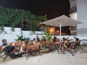 a group of people sitting at tables and an umbrella at Hostel K13 in Sarandë