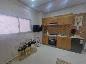 a kitchen with wooden cabinets and tables and a window at Best Appertement in haut founty in Agadir