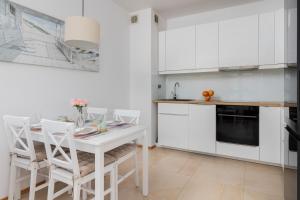 kuchnia z białymi szafkami oraz białym stołem i krzesłami w obiekcie Beautiful Apartment Gdynia Czarnieckiego with Balcony by Renters w mieście Gdynia