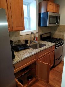 a kitchen with a sink and a stove and a microwave at Wonderful & Cozy Apartment Close to Time Square NYC in North Bergen