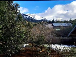 una casa y árboles con vistas a las montañas cubiertas de nieve en Cabaña en Villa Los Coihues en San Carlos de Bariloche