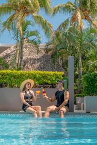 um homem e uma mulher sentados ao lado de uma piscina em Hotel Roca Sunzal em La Libertad