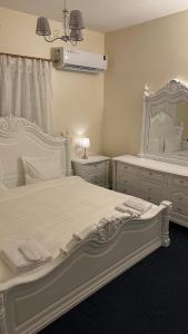 biała sypialnia z dużym łóżkiem i lustrem w obiekcie فيلا ممشى الضباب w mieście Abha