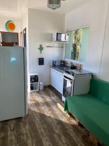 a kitchen with a green couch and a refrigerator at Casa Container Praia do Rosa - 01 Ibiraquera in Imbituba