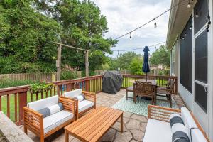 eine Terrasse mit 2 Stühlen und einem Holztisch in der Unterkunft Burnside Beauty 4BR Pingpong Patio in Tallahassee