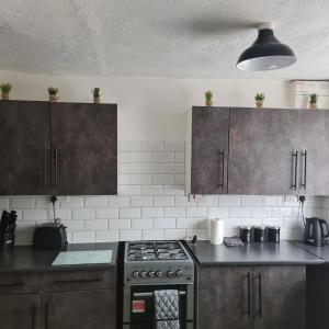a kitchen with brown cabinets and a stove top oven at Freshen-Up Stays in Oakengates
