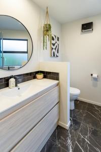 a bathroom with a sink and a mirror at Downtown Delight 2 Bed 1 Bath - Single Garage in Christchurch +28 photos