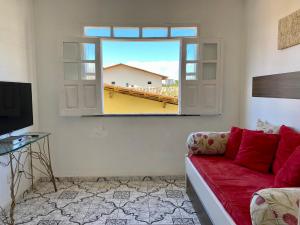 a living room with a red couch and a window at Kalug - DUPLEX com 3 QUARTOS em condomínio com PORTARIA 24 HORAS, WI-FI 200mbps e COZINHA COMPLETA na PRAIA DOS MILIONÁRIOS in Ilhéus