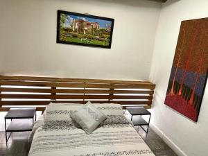 a bedroom with a bed with two chairs and a picture on the wall at Hostel Once Once in Villa de Leyva