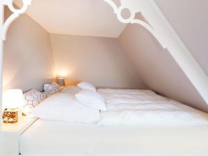 a white bed with white pillows in a attic at Watthues in Kampen