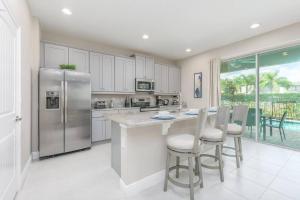 a kitchen with a stainless steel refrigerator and white cabinets at Luxury 6 BR 6 Bath @Encore Resort Pool Spa Grill. in Orlando