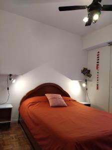 una camera con letto arancione e ventilatore a soffitto di FLORESTA, cómodo departamento en CABA a Buenos Aires