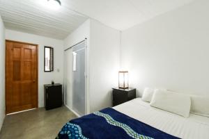 une chambre blanche avec un lit et une porte en bois dans l'établissement Casa Morenita mía, à San Cristóbal de Las Casas