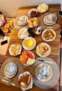 a wooden table topped with plates of breakfast foods at Kaha Mar - Patacho in Pôrto de Pedras