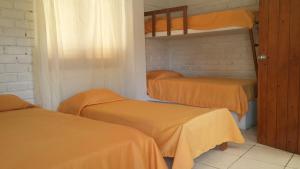 Cette chambre comprend 3 lits superposés avec des draps orange. dans l'établissement Villa Belluno, à Zorritos