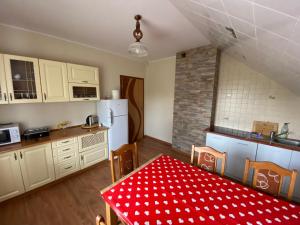 a kitchen with white cabinets and a table with a red table cloth at Gospodarstwo Agroturystyczne Zasadkowe Bory in Rogowo