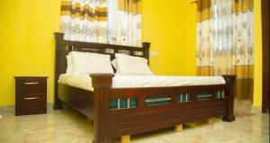 ein Schlafzimmer mit einem Holzbett mit gelber Wand in der Unterkunft Extended stay suite, Tema. in Ashaiman