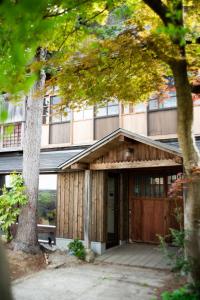 un edificio con una puerta de madera y un árbol en 草木ももとせ 