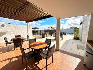 un patio con mesas y sillas en una terraza en Apto Facilties 250m Praia Ponta Verde Luxo, en Maceió