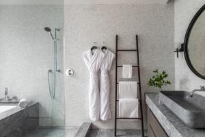 a bathroom with a shower with white robes hanging on the wall at Alila Napa Valley, a Hyatt Resort in St. Helena