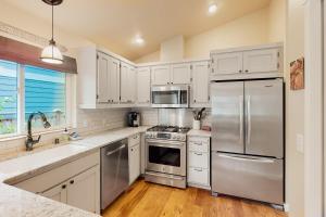 a kitchen with white cabinets and a stainless steel refrigerator at Island Cottage in Madrona Beach
