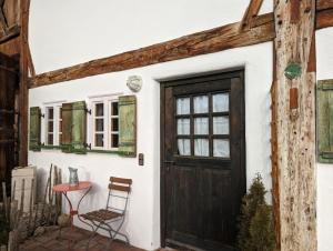 a door to a house with a table and a chair at Herzstuecke-Ferienwohnung in Ingenried