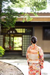 Una donna in un kimono davanti a un palazzo di ‐izen 高田‐ 楽酔亭 a Jōetsu