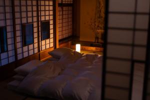 un letto con lenzuola bianche in una stanza con finestra di ‐izen 高田‐ 楽酔亭 a Jōetsu