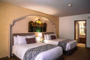 Habitación de hotel con 2 camas y espejo en Quinta Real Zacatecas en Zacatecas