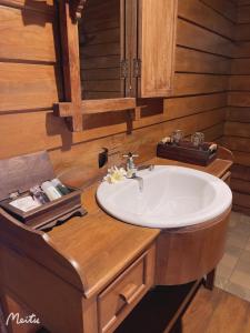 ein Badezimmer mit einem weißen Waschbecken und Holzwänden in der Unterkunft Lantana House in Ban Pa Muang