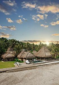 a group of huts with palm trees in the background at Sumba Beach House in Waikabubak