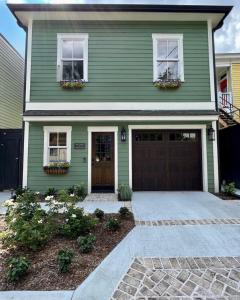 a green house with two windows and a garage at New Construction Cottage in Downtown Savannah Arts District in Savannah