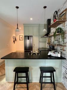 a kitchen with a black counter and two stools at New Construction Cottage in Downtown Savannah Arts District in Savannah