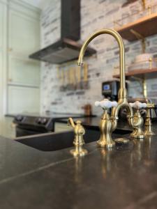 a kitchen sink with gold faucets on a counter at New Construction Cottage in Downtown Savannah Arts District in Savannah