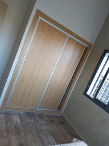 uma porta de madeira num quarto com uma janela em Residance Perla Bouznika em Bouznika