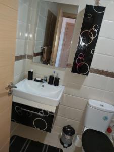 uma casa de banho com um lavatório, um WC e um espelho. em Residance Perla Bouznika em Bouznika