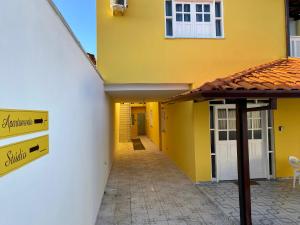 un edificio amarillo con un cartel en el costado en Kalug - Apto em Guest House em Condomínio na Praia do Sul, en Ilhéus