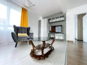 a living room with a table and a chair at YamaLuxe Apartments - WestSide 2 in Floreşti