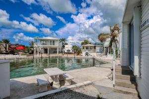 a swimming pool with a bench in front of a house at Dock Holiday in Cudjoe Key
