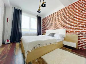 Un dormitorio con una pared de ladrillo y una cama en YamaLuxe Apartments - WestSide 2, en Floreşti