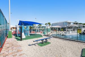 a playground with a blue bench next to a pool at Dock Holiday in Cudjoe Key