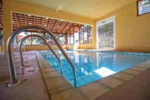a swimming pool with stairs in a building at VELINN Hotel Ninho do Falcão in Monte Verde