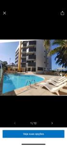 uma imagem de uma piscina com cadeiras e um edifício em Hotel Victory flat em Cabedelo