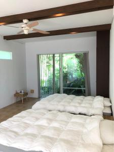 Cama blanca grande en habitación con ventilador de techo en 727セブンツーセブン石垣島ベース, en Ishigaki Island