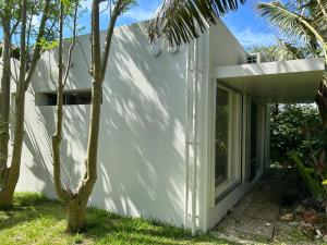 a white house with a window and a palm tree at 727セブンツーセブン石垣島ベース in Ishigaki Island