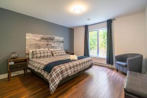 ein Schlafzimmer mit einem Bett, einem Stuhl und einem Fenster in der Unterkunft Grands Espaces Orford 115 condo/chalet in Orford