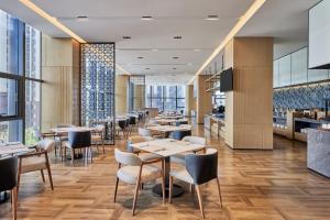 um restaurante com mesas, cadeiras e janelas em Fairfield by Marriott Zibo em Zibo