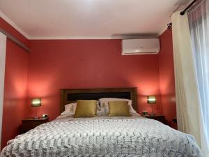 een slaapkamer met rode muren en een bed met gele kussens bij Alojamiento Los Nogales in Santa Cruz