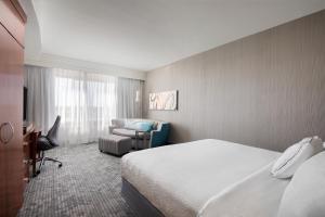 a hotel room with a bed and a chair at Courtyard by Marriott Fort Smith Downtown in Fort Smith